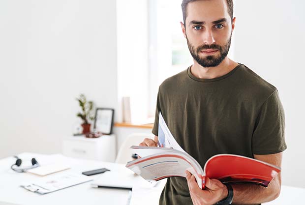 Produktkataloge als Musterbuch drucken ein Mann hält einen Katalog mit Klebebindung in der Hand und sucht darin